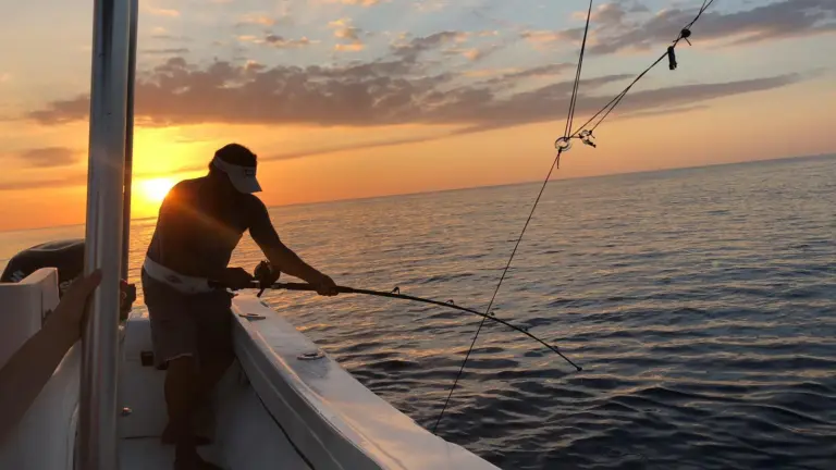 An angler fights a fish from the boat as the sun sets over the Pacific off Nosara.