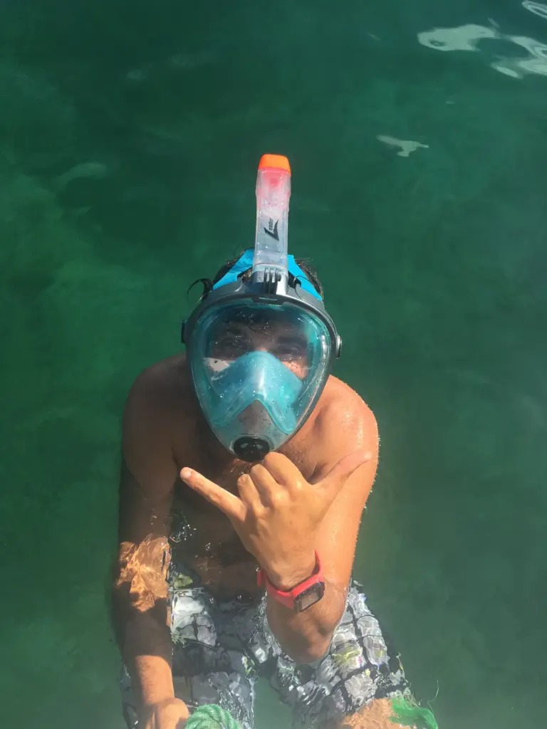 A snorkeler in a full-face mask floats over the reef in clear green water near Nosara.