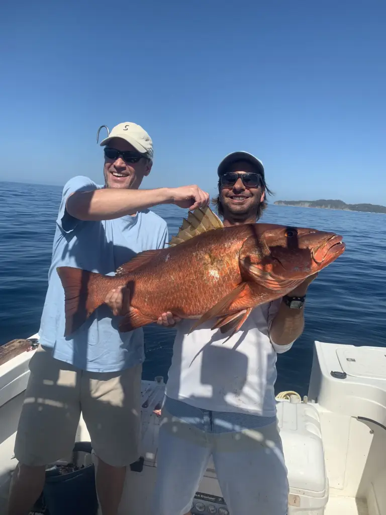Two guests hold a large cubera snapper caught near the rocks off Nosara.