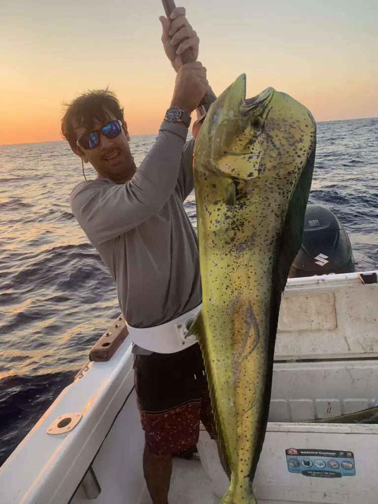An angler holds a large mahi-mahi at sunset on the boat off Nosara.
