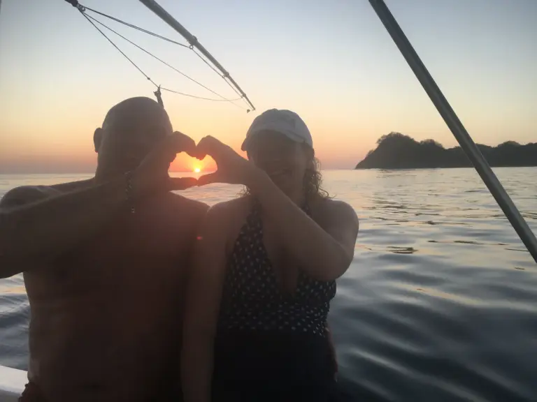 A couple frames the setting sun with their hands during a sunset cruise off Nosara.