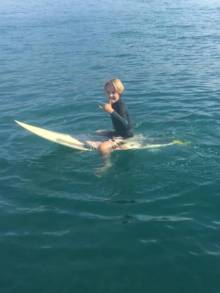 A young guest sits on a paddleboard in clear turquoise water near Nosara.