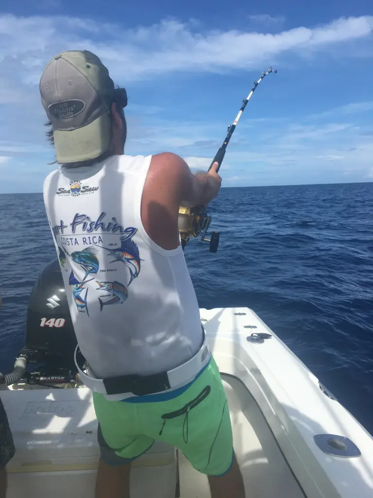 An angler in a Sea Saw shirt fights a fish with the rod bent double off Nosara.