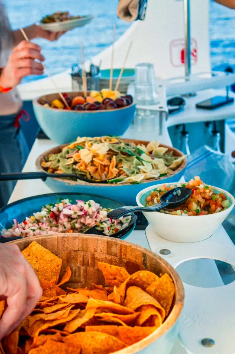 A guest serves from bowls of fresh fruit, pasta salad, ceviche and nachos set out on the boat.