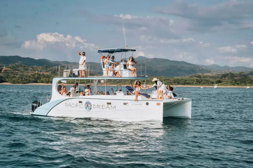 The catamaran runs close to the forested Guanacaste coastline with guests on both decks.