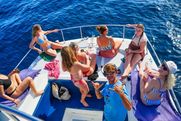 A crew member sits with guests on the catamaran's bow during a tour off the Nosara coast.
