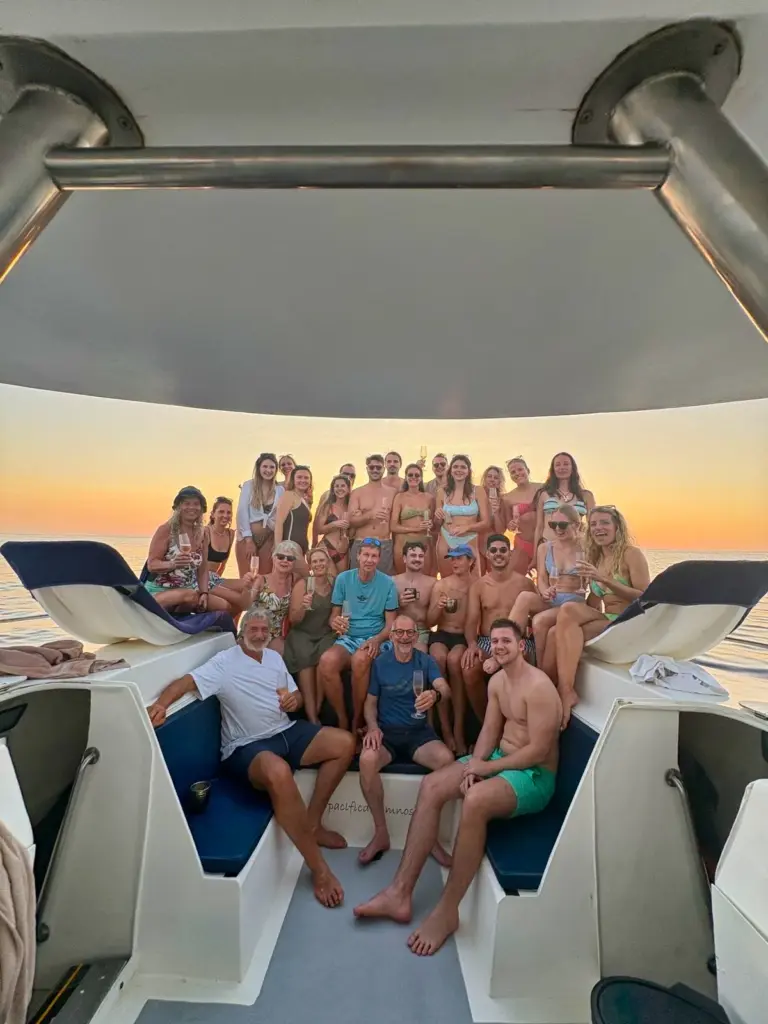 Guests fill the catamaran's stern seating as the sky turns gold behind them off Nosara.