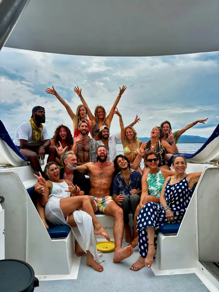 A large group of guests cheers together on the catamaran's stern seating off Nosara.