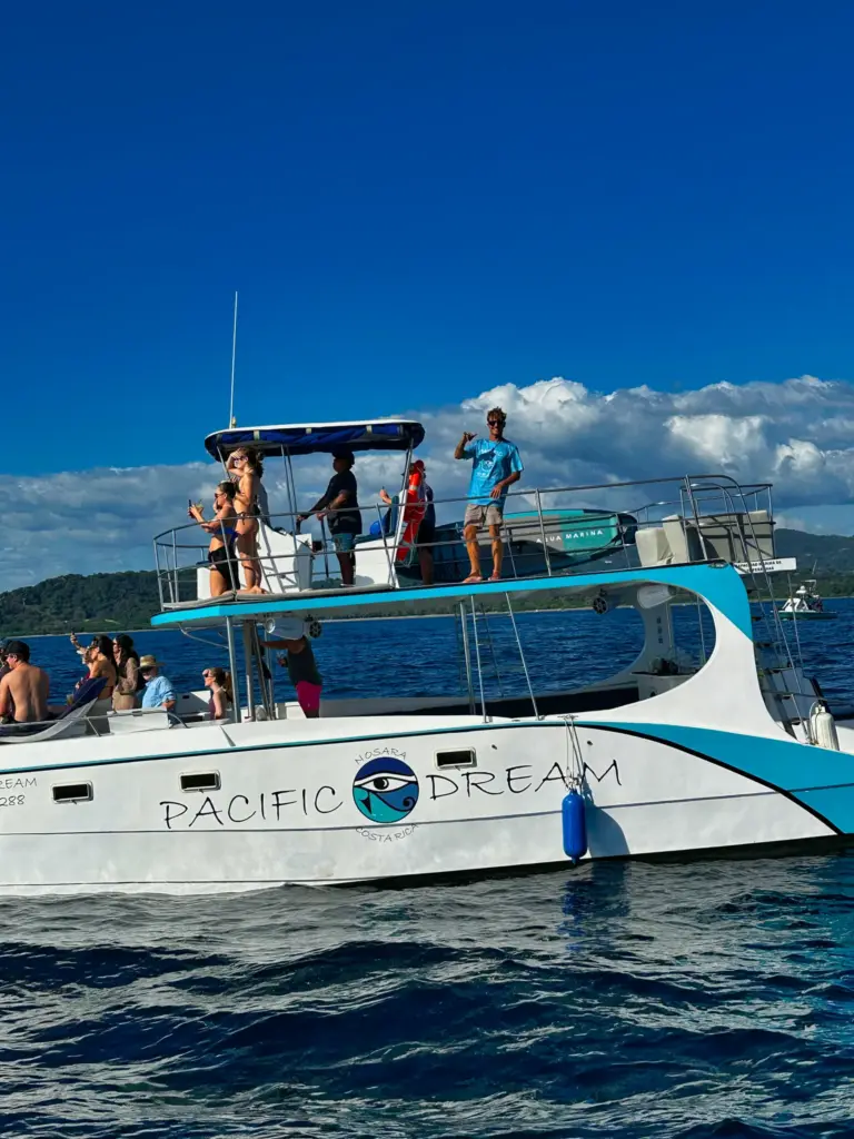 Guests fill the catamaran's upper and lower decks on a bright day off the Nosara coast.