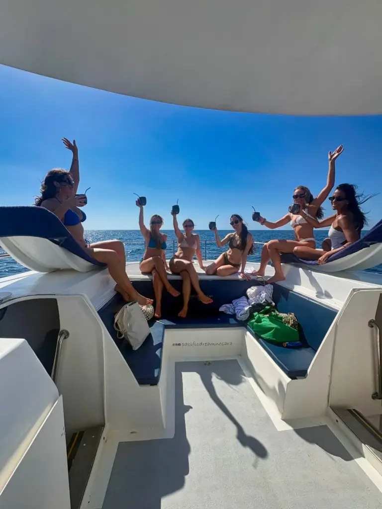 Guests raise their drinks and cheer from the catamaran's stern seating off Nosara.