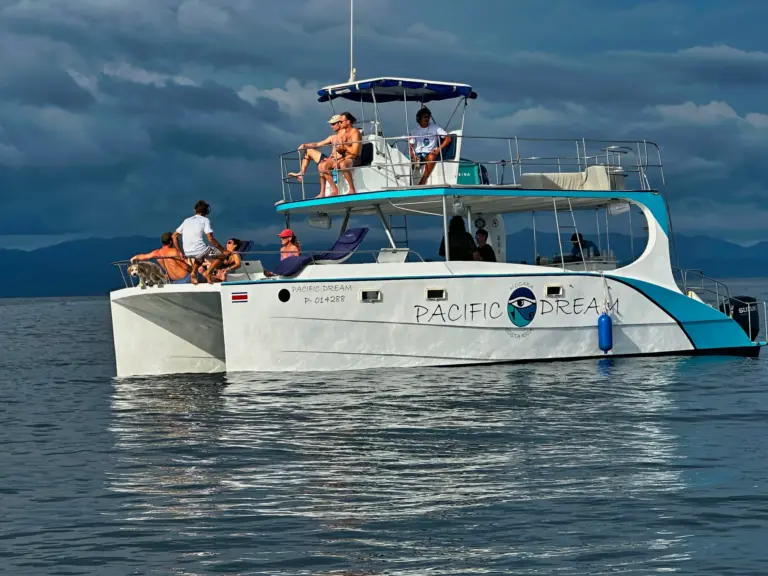 A side view of the catamaran with guests on both decks under a grey sky.