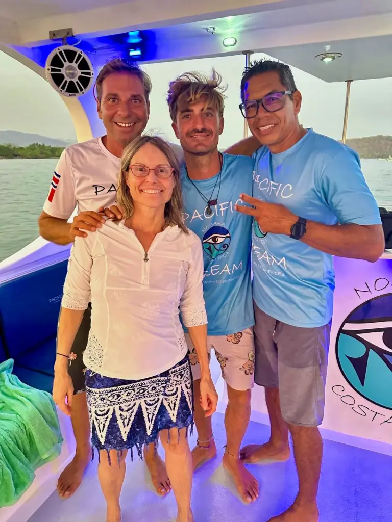 Guests and crew pose on the lit boat deck at dusk after a day on the water in Nosara.