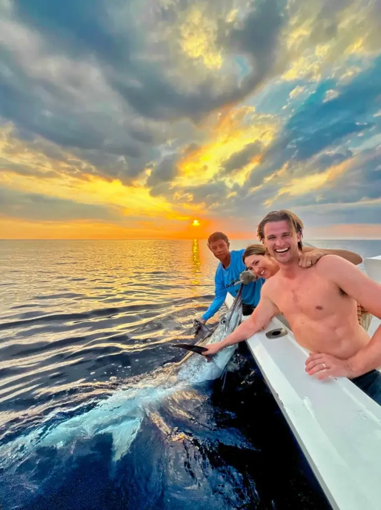 Guests bring a fish alongside the boat as the sun sets over the Pacific off Nosara.