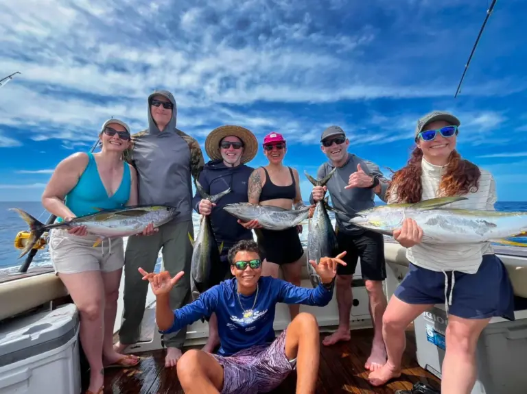 A group of guests hold up tuna, mahi-mahi and roosterfish on deck after a day fishing from Nosara.