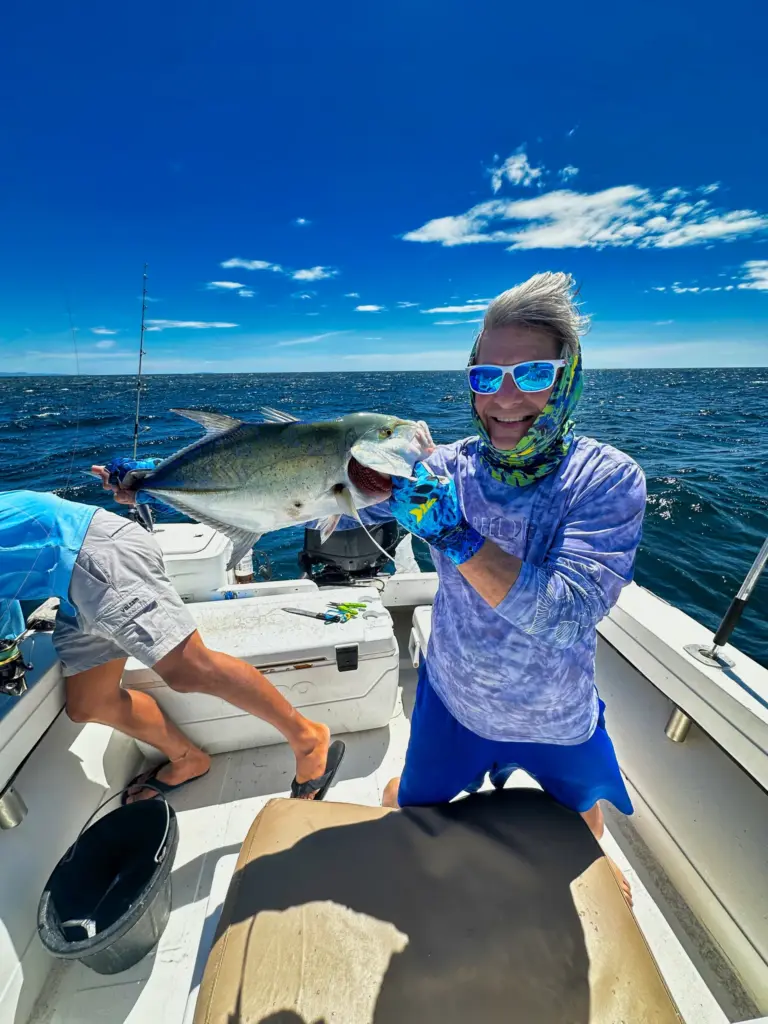 An angler smiles as an amberjack is lifted aboard on the gaff off the Nosara coast.