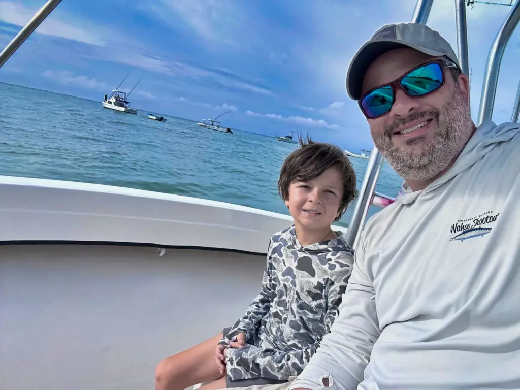 The captain sits with a young guest at the console with the Nosara anchorage behind.