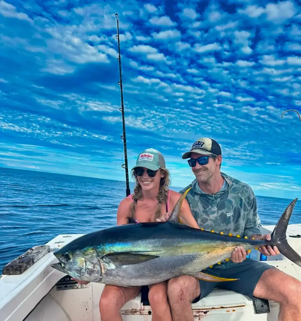 A couple sits with a large yellowfin tuna across the deck after landing it off Nosara.