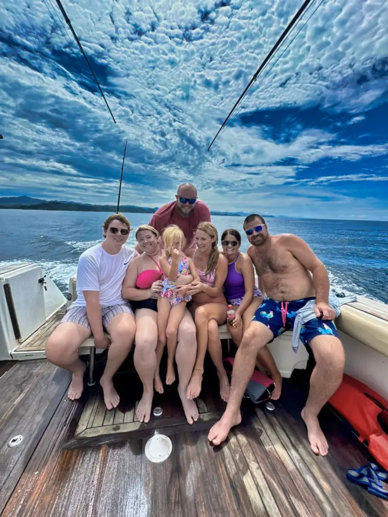 A family sits together on the boat's teak deck under a mackerel sky off Nosara.