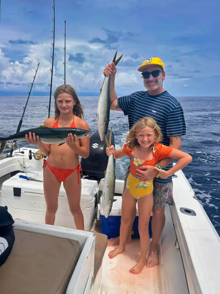 A father and two young daughters hold up their catch on the boat's bow off Nosara.