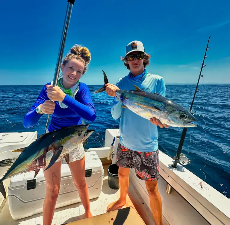 A guest and a crew member hold two tuna on the deck during an inshore trip from Playa Garza.