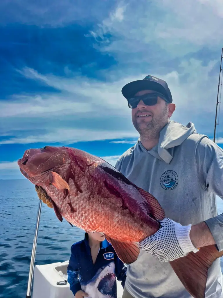 A guest holds a heavy cubera snapper on the deck after an inshore trip from Playa Garza.