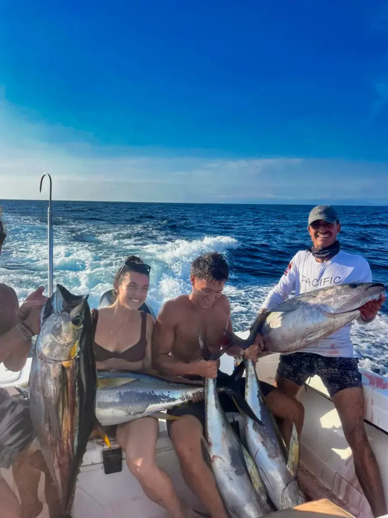 Guests and a crew member hold several tuna along the stern after a morning inshore trip.