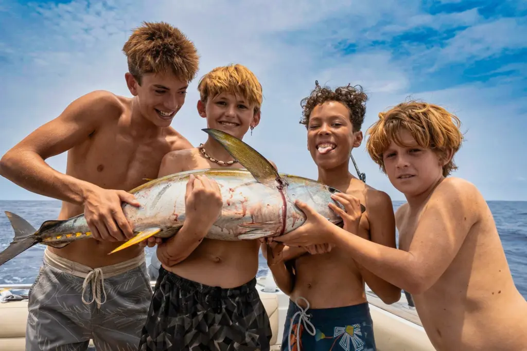 Four young guests hold up an amberjack together on the boat off the Nosara coast.