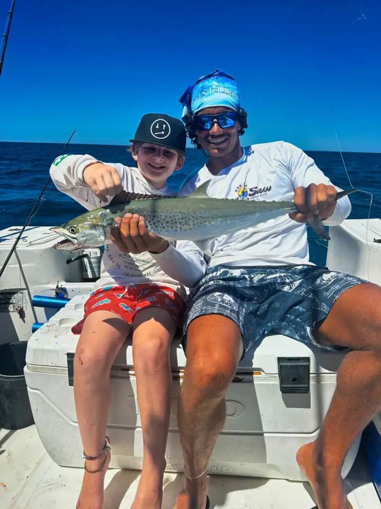 A young guest and a crew member hold a Spanish mackerel on the boat off the Nosara coast.