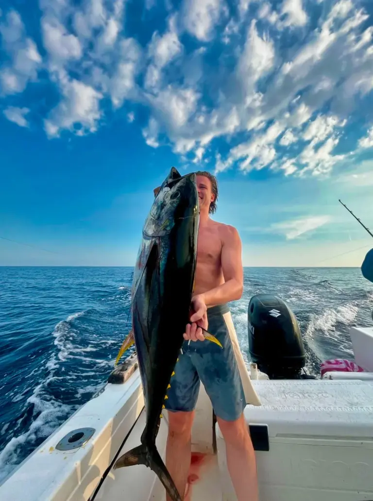 An angler holds a heavy tuna at the stern under a bright Costa Rican sky.