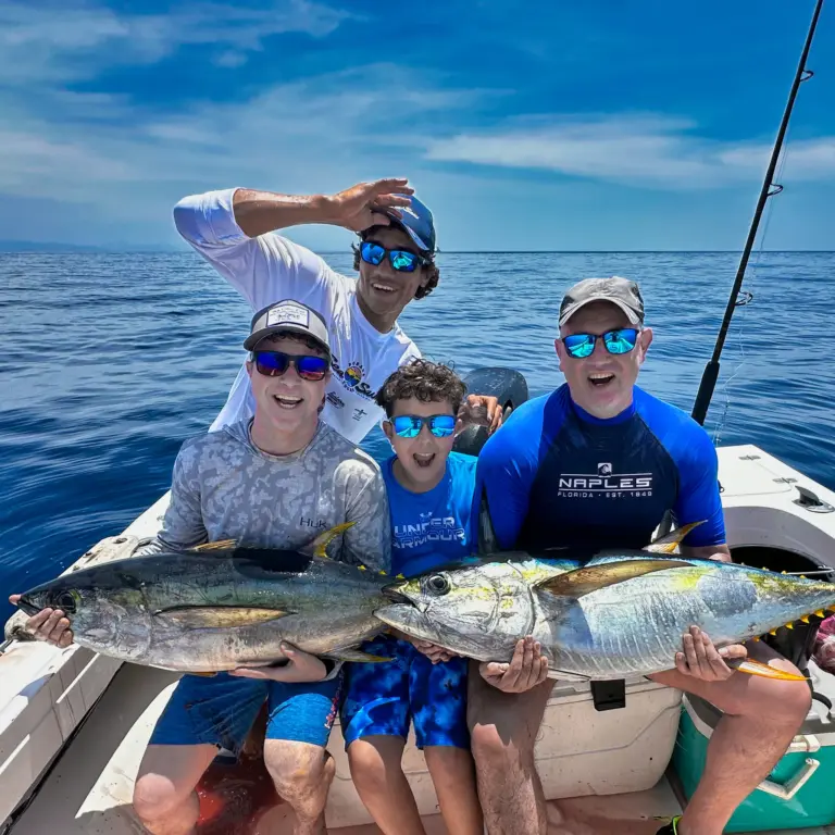 A family and the crew hold three yellowfin tuna across the cockpit after an offshore trip.