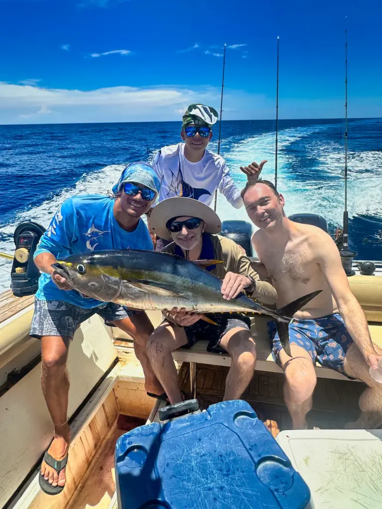 Three guests and a crew member hold a yellowfin tuna across the cockpit off Nosara.