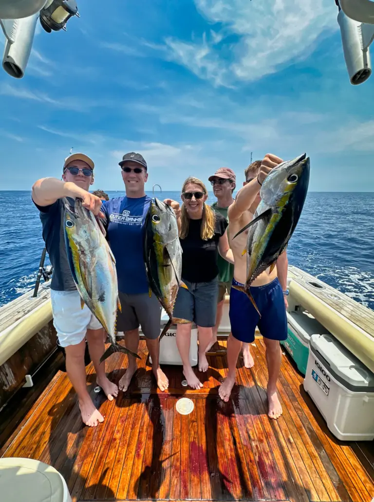 A group of guests holds up four yellowfin tuna on the boat's teak deck off Playa Garza.