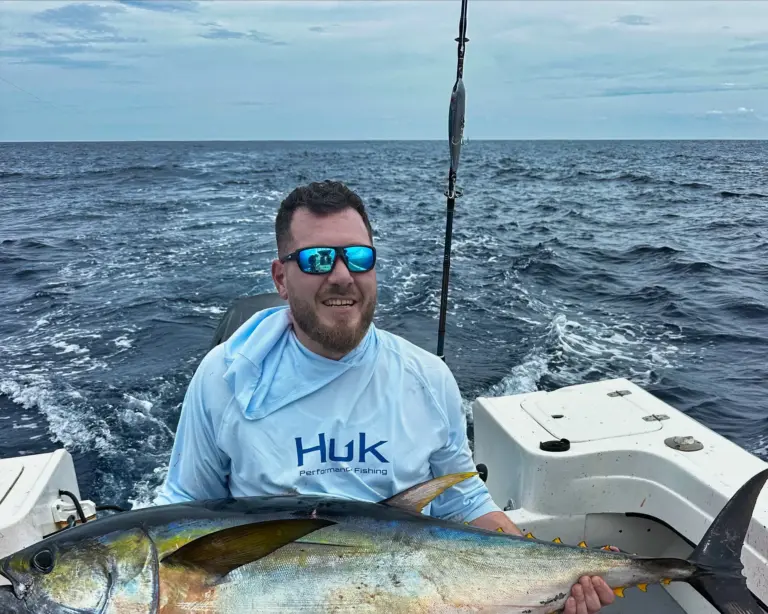 A guest sits in the fighting chair holding a yellowfin tuna across his lap off Nosara.