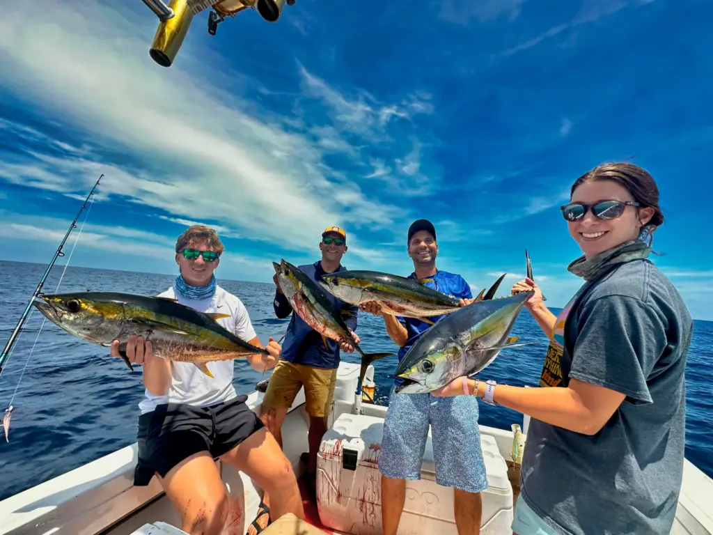 Guests and crew hold up yellowfin tuna and a mahi-mahi at the stern off Nosara.