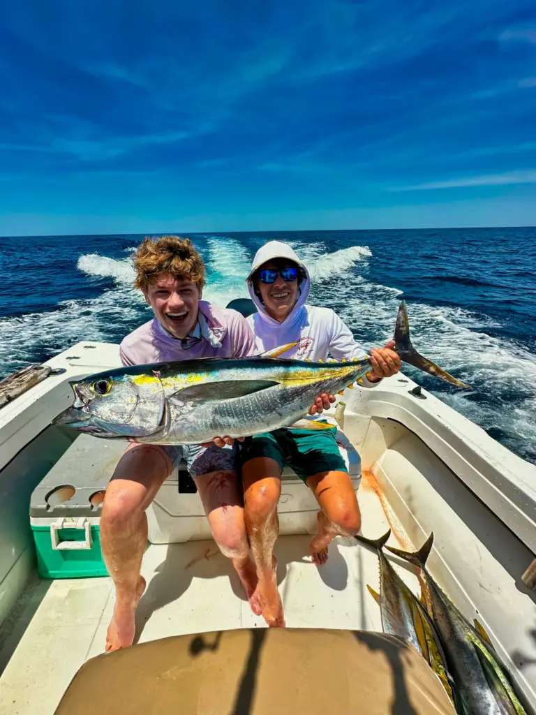 Two guests hold a yellowfin tuna across the cockpit while the boat runs back to Nosara.