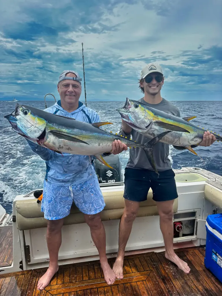 Two guests hold four yellowfin tuna between them on the boat's teak deck off Nosara.