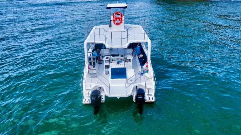 Aerial top-down view of the catamaran with guests on deck in blue water off Nosara.