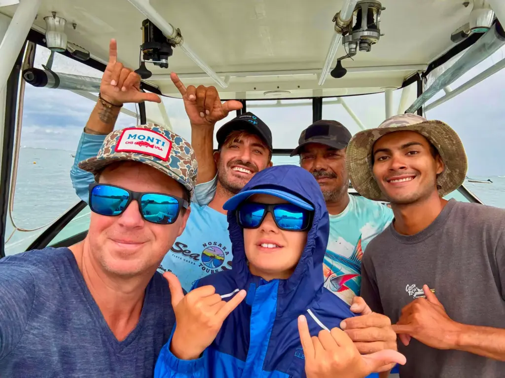 A guide, crew and young guest pose for a selfie on the boat during a tour from Nosara.