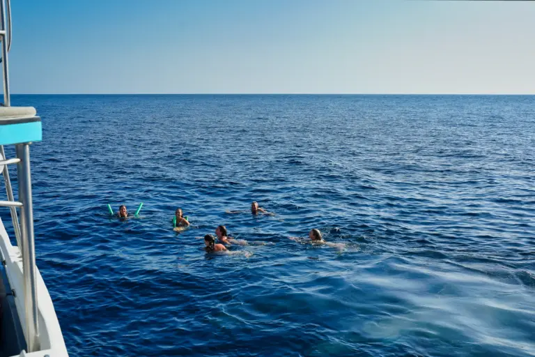 Guests float and snorkel in calm blue water beside the boat off the Nosara coast.
