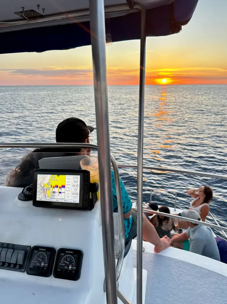 The captain steers from the helm station while the sun sets over the Pacific off Nosara.