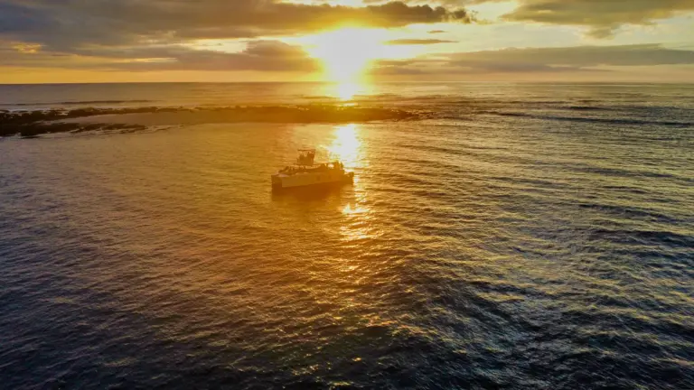 Aerial view of the catamaran silhouetted on the golden path of the setting sun off Nosara.
