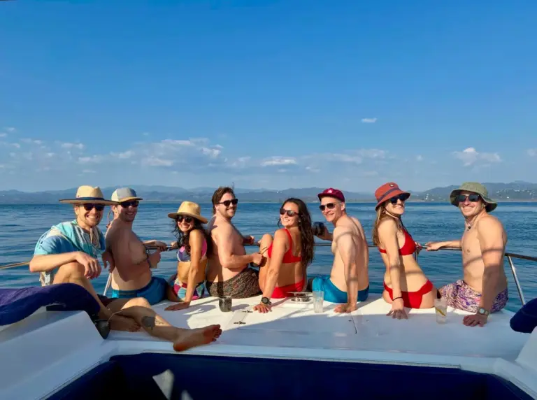 Guests gather on the catamaran's bow with the green Guanacaste coastline in the distance.
