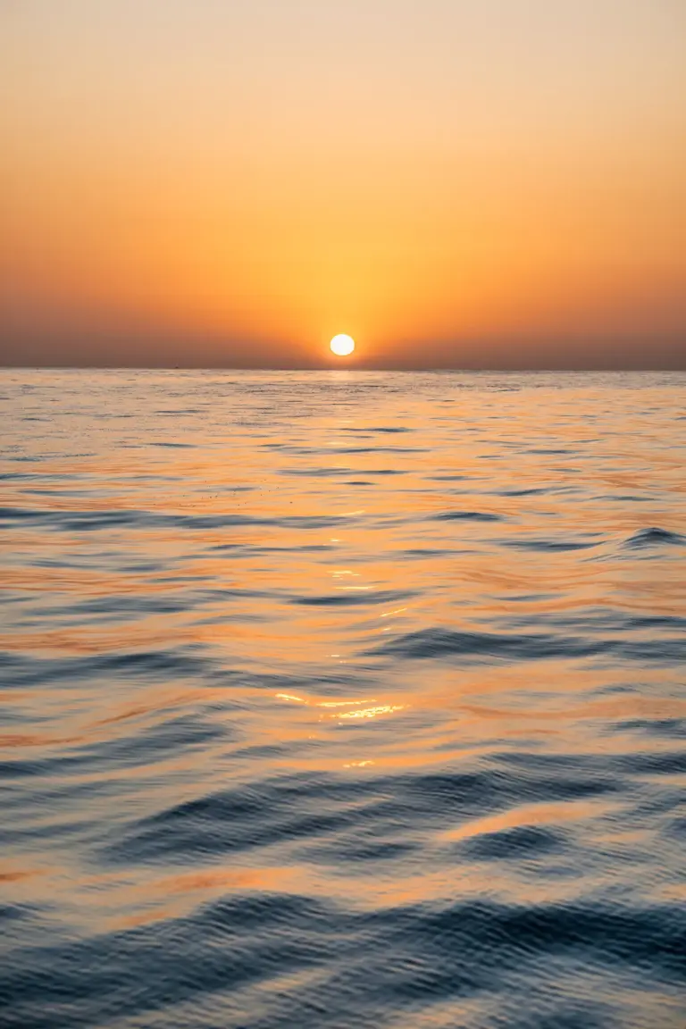 The last of the sun meets the Pacific horizon on a calm evening off Nosara, Costa Rica.