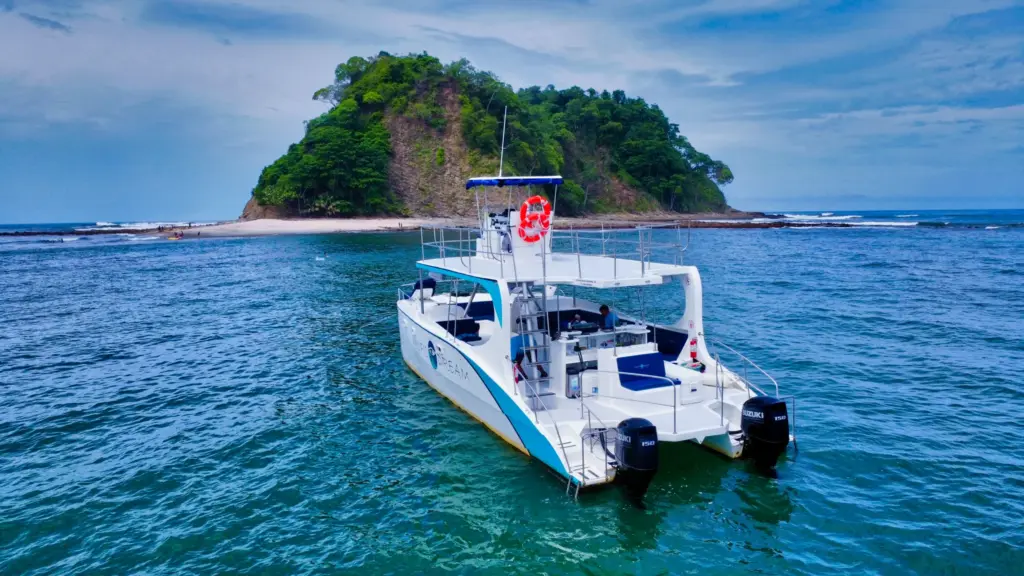 The catamaran sits anchored beside a small forested island on the Guanacaste coast.