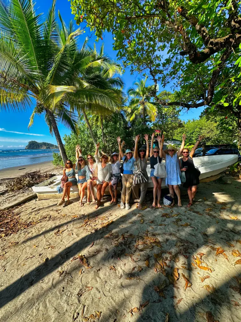 A large group celebrates under the palm trees on the beach beside the boats at Playa Garza.