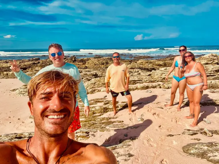 A guide takes a selfie with guests on a rocky beach during a stop on the Nosara coast.